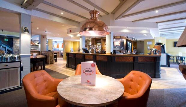 Bar area at Premier Inn Manchester (Heaton Park) hotel showing tables, chairs and lighting 